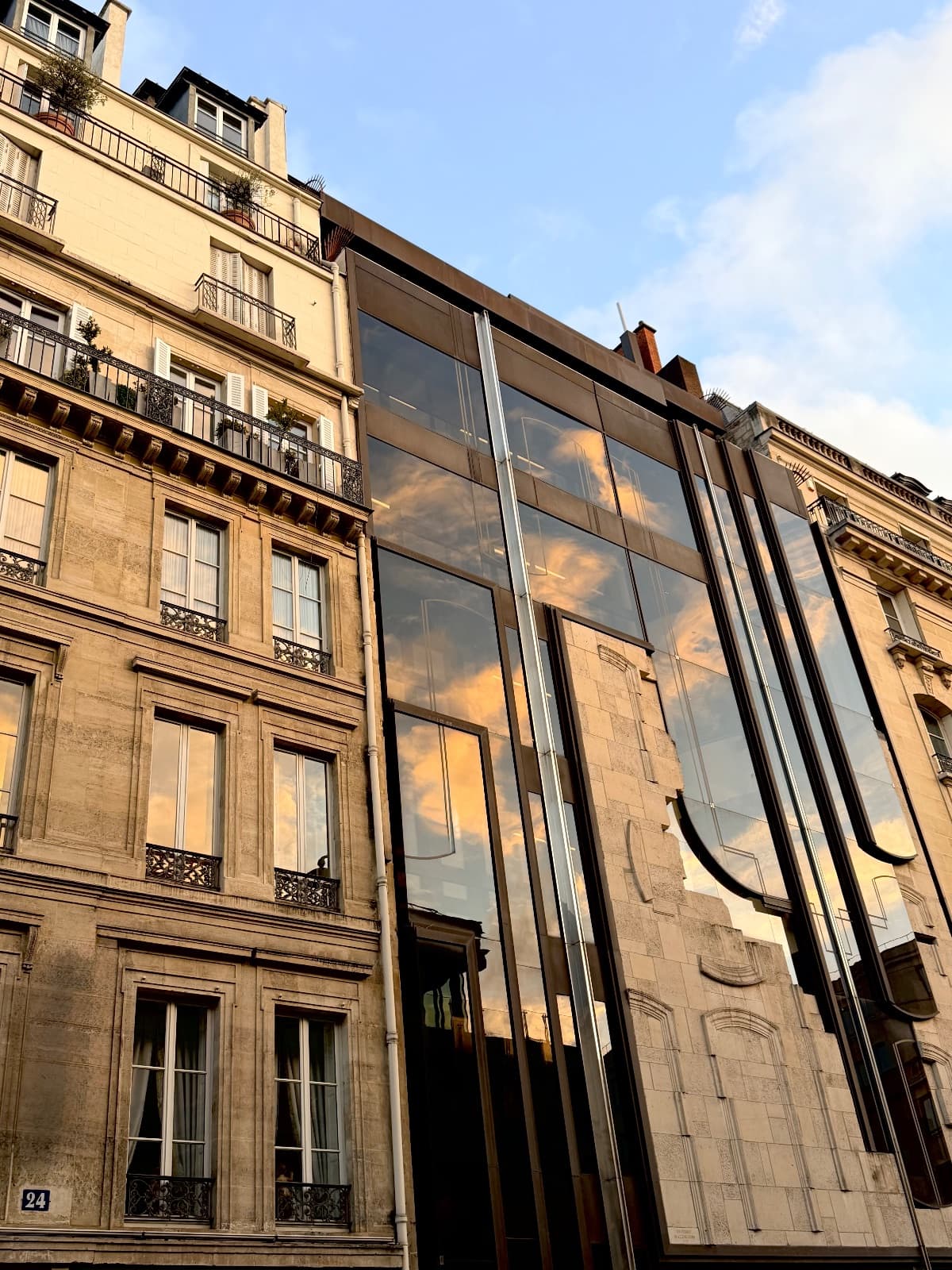 A Parisian building facade with classic stone architecture and a modern glass reflection