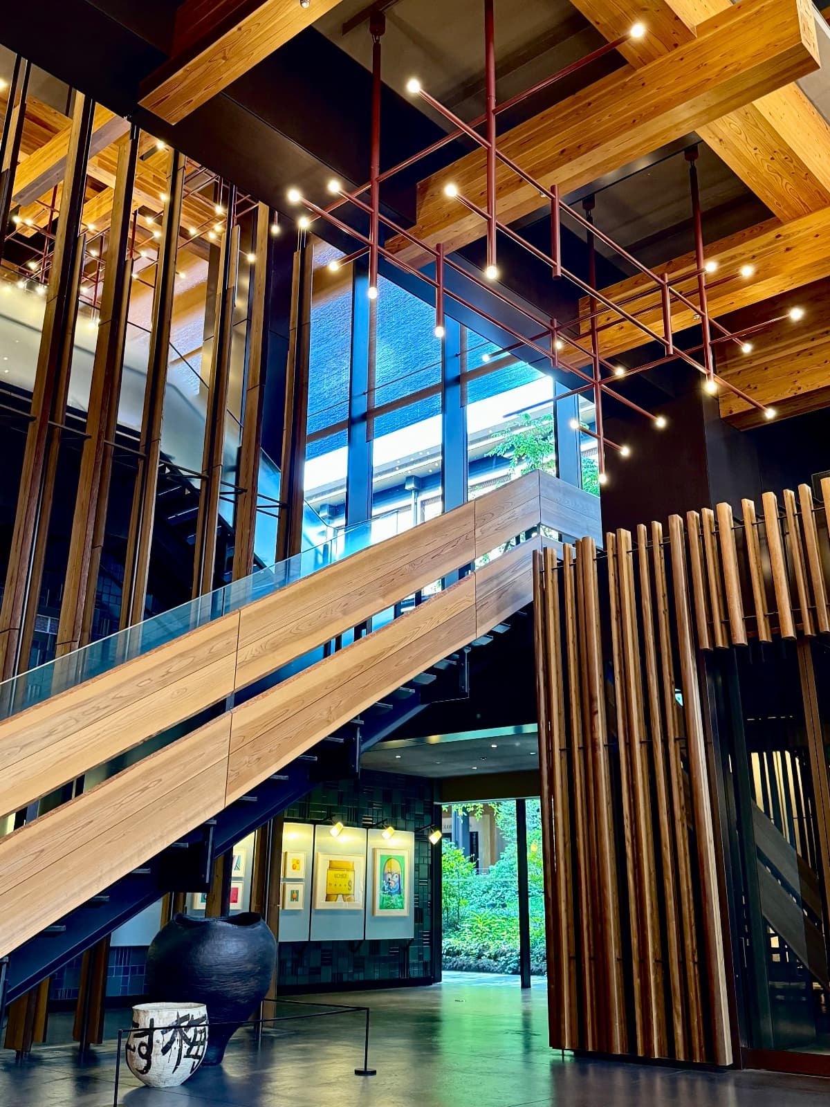 A timber and steel staircase in a Japanese building lobby with warm pendant lighting