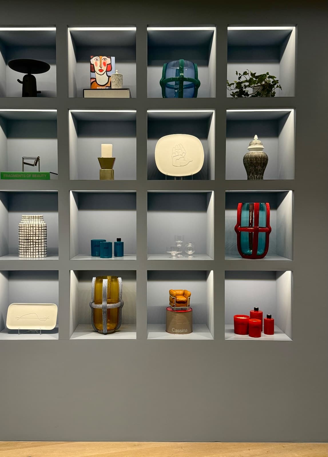 A curated wall of illuminated display niches holding vases, ceramics, and objects in Japan